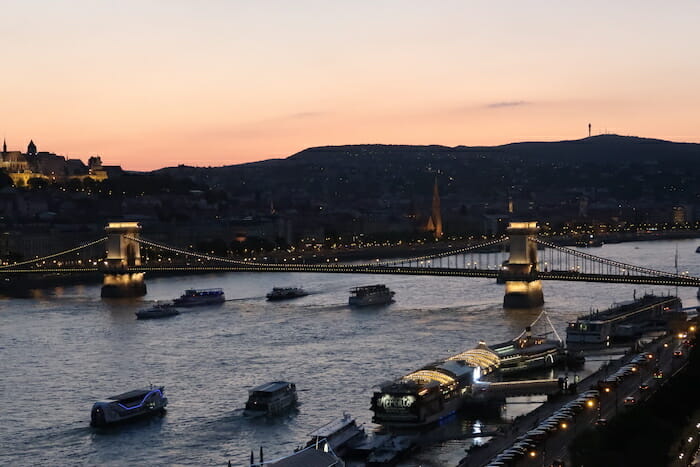 a bridge over water with boats and a city in the background