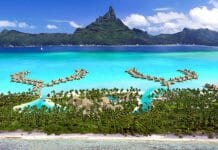 a tropical island with huts and a beach with Bora Bora in the background