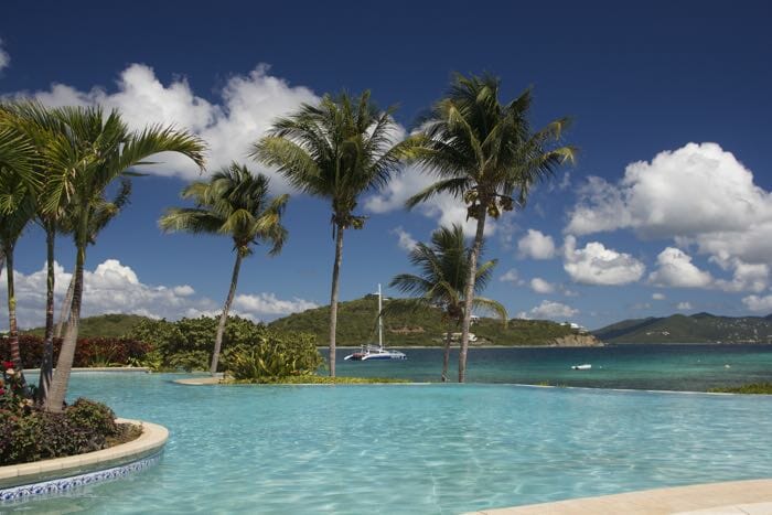 a pool with palm trees and a boat in the background