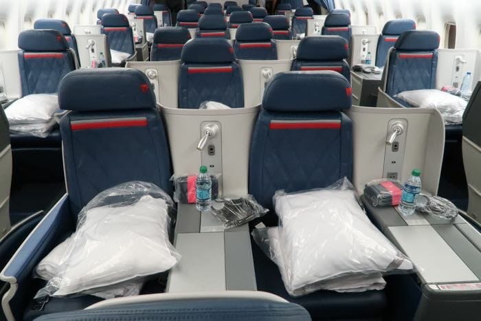 a seat of an airplane with a few pillows and a bottle of water