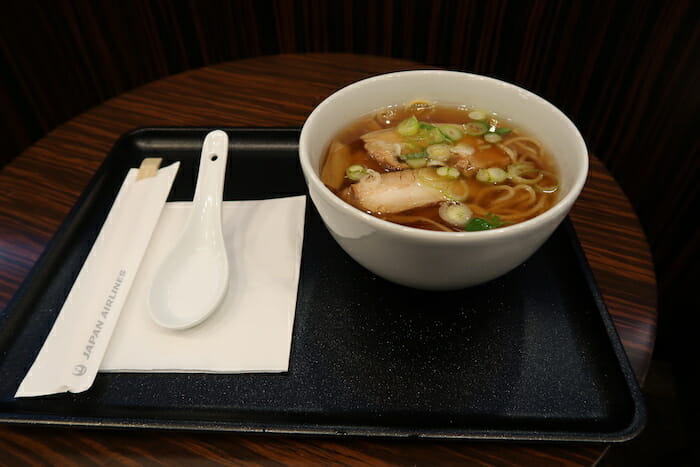 a bowl of soup with noodles and vegetables on a tray