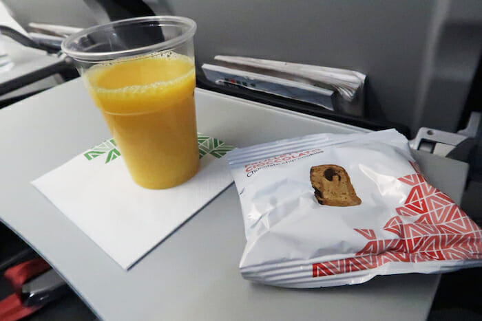 a plastic cup of orange juice next to a bag of food