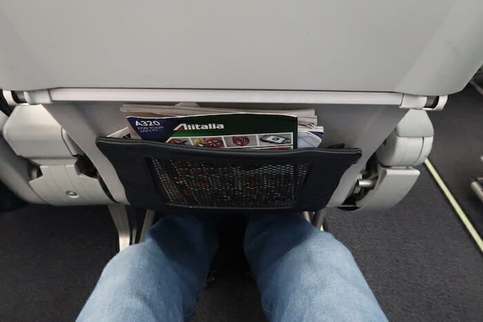 a person's legs and a pocket in an airplane seat