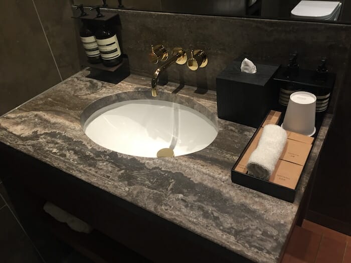 a sink with a gold faucet and a black and white towel