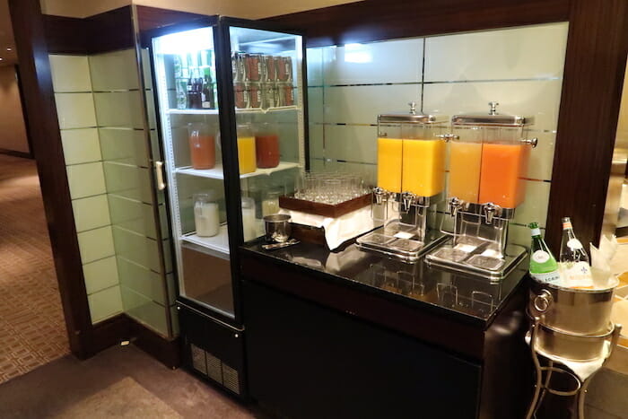 a beverage dispenser with orange juice in a glass case