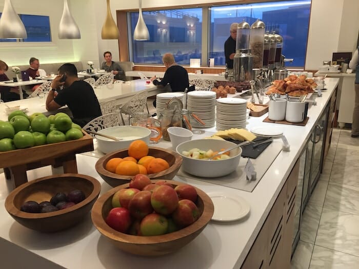 a buffet with many bowls of fruit and plates