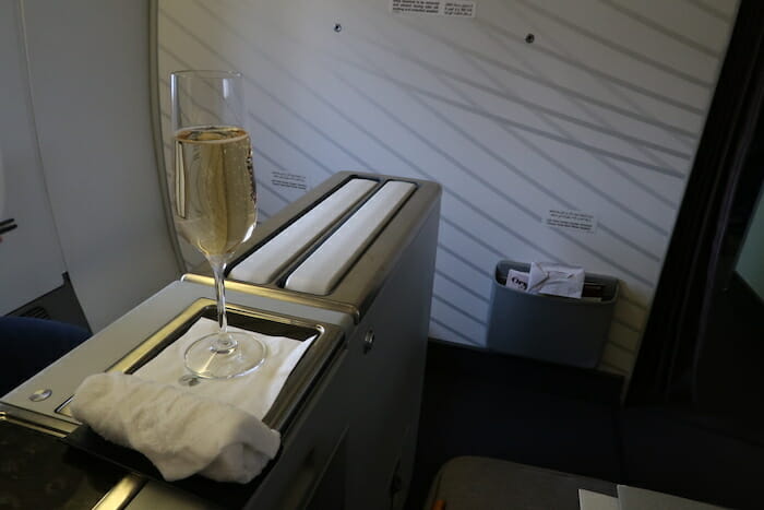 a glass of champagne on a tray in a plane