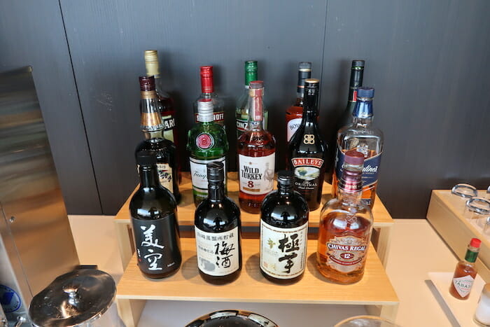 a group of bottles of alcohol on a wooden shelf