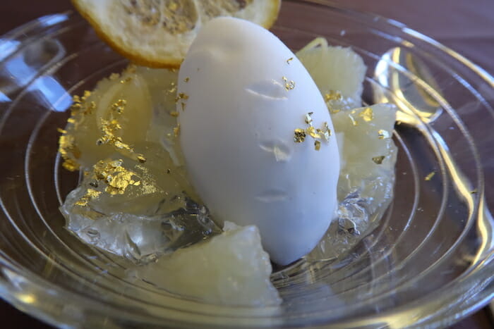 a white egg with gold flakes on top of a lemon slice