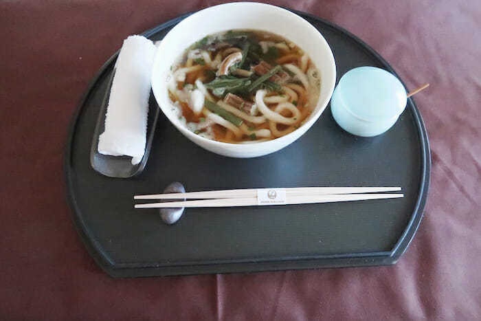 a bowl of soup with chopsticks and a spoon on a tray