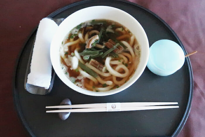 a bowl of soup with chopsticks and a napkin on a tray