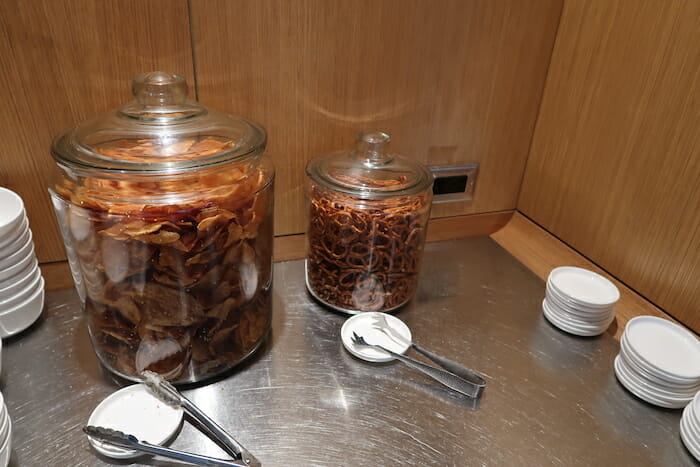 a glass jars of pretzels and tongs on a counter