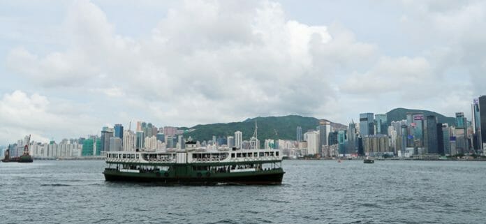 a boat in the water with Victoria Harbour in the background