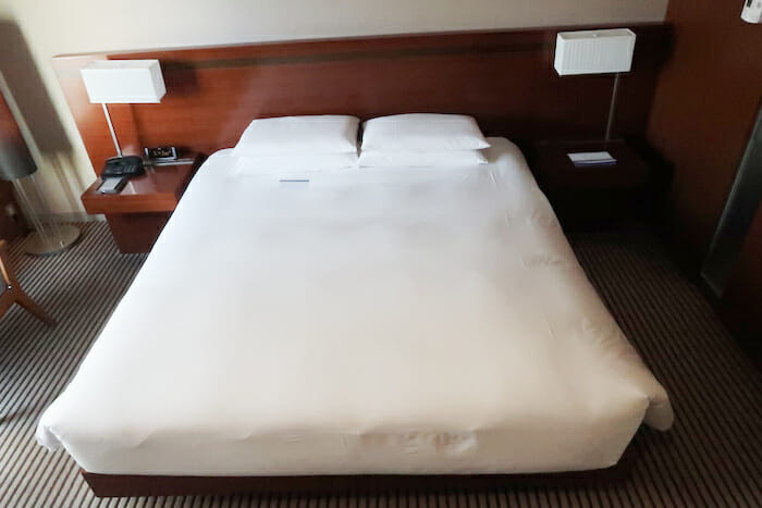 a bed with white sheets and a wood headboard