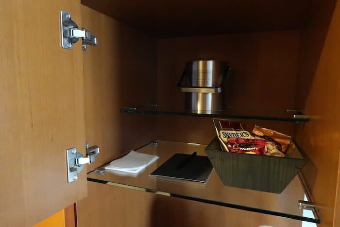 a glass shelf with a bowl of snacks and a silver container