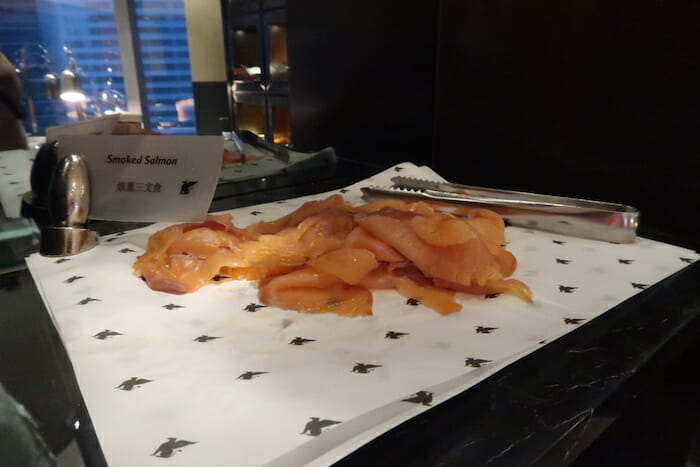 a pile of raw salmon on a paper with tongs