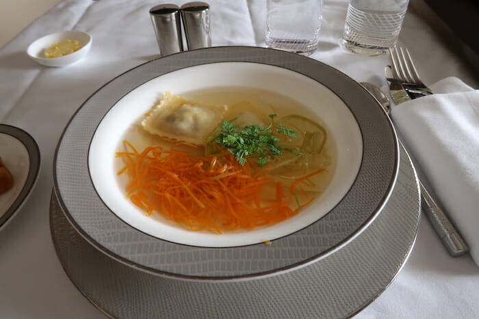 a bowl of soup with carrots and a piece of meat