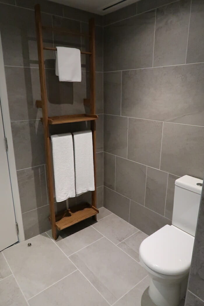 a bathroom with a toilet and a shelf with towels