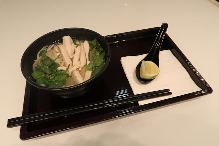 a bowl of soup with chopsticks and a spoon on a tray