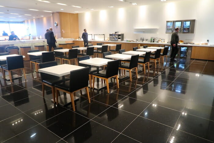 a group of people standing in a room with tables and chairs