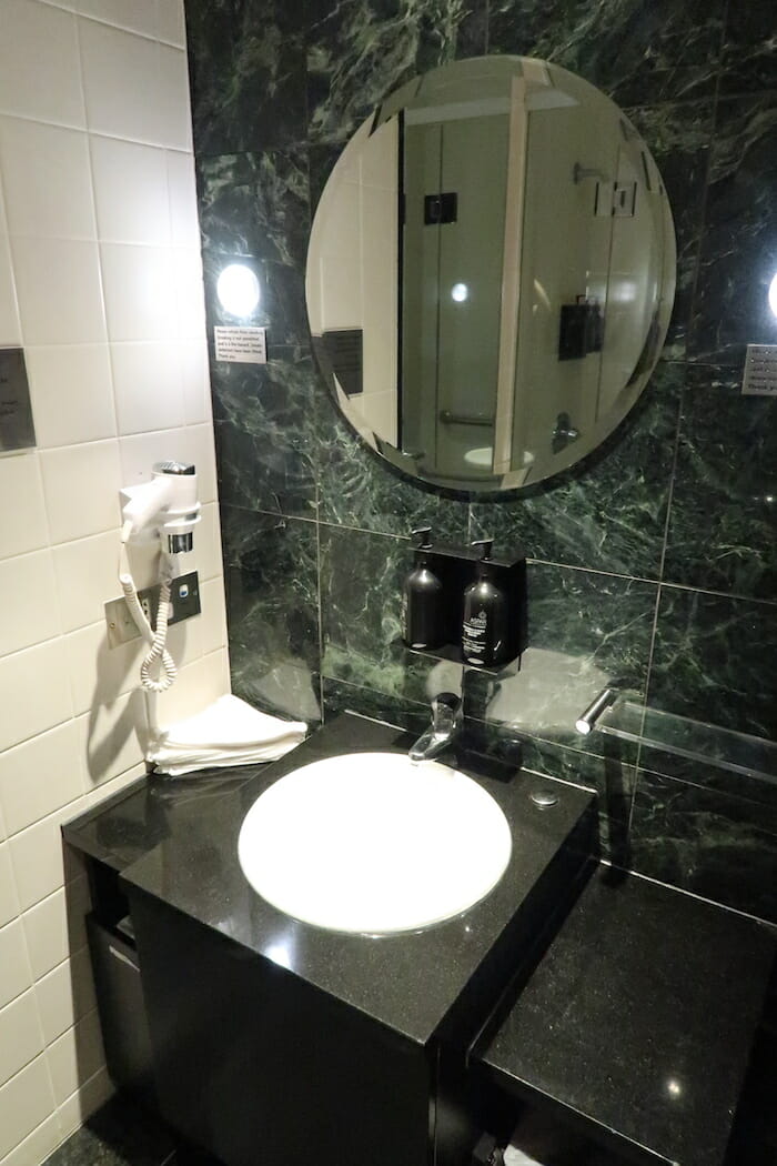 a bathroom with a round mirror and a sink