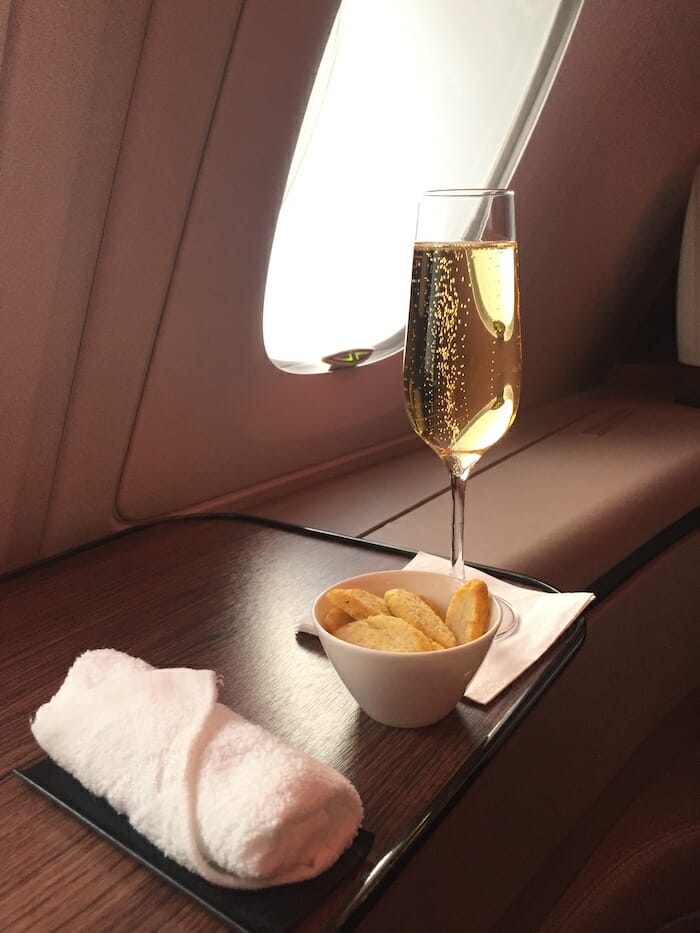 a glass of champagne and a bowl of crackers on a tray