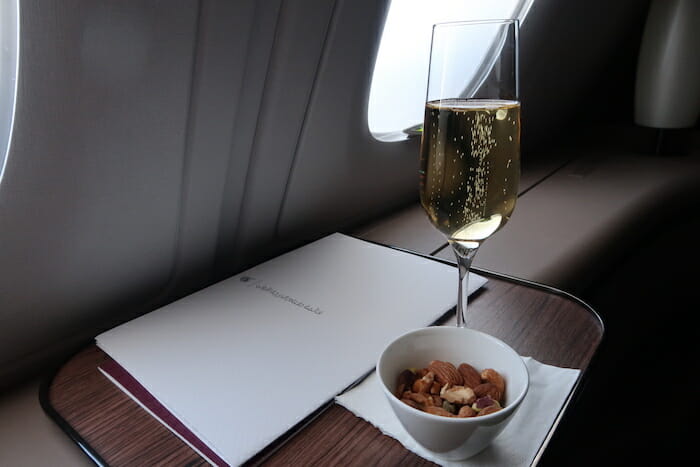 a glass of champagne and a bowl of nuts on a table