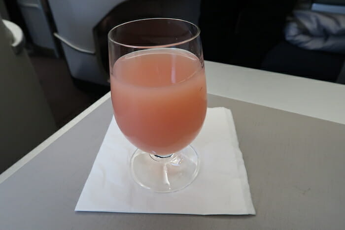 a glass of pink liquid on a napkin