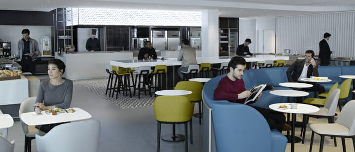 a man reading a magazine in a room with people sitting around