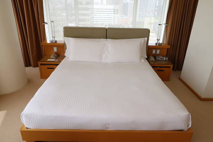 a bed with white sheets and a lamp on the side