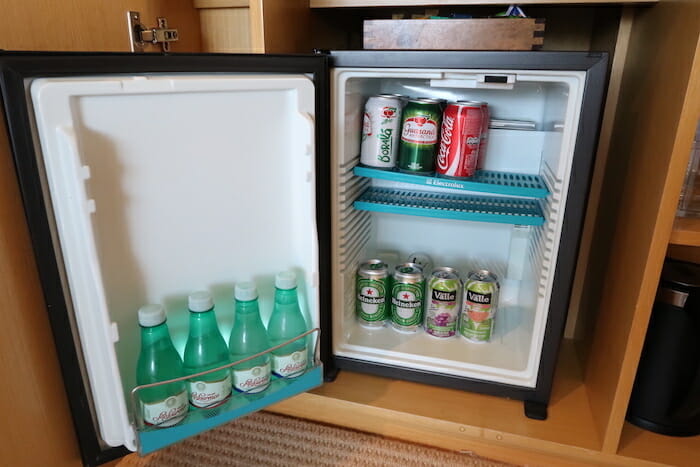 a mini fridge with cans of soda and cans of water