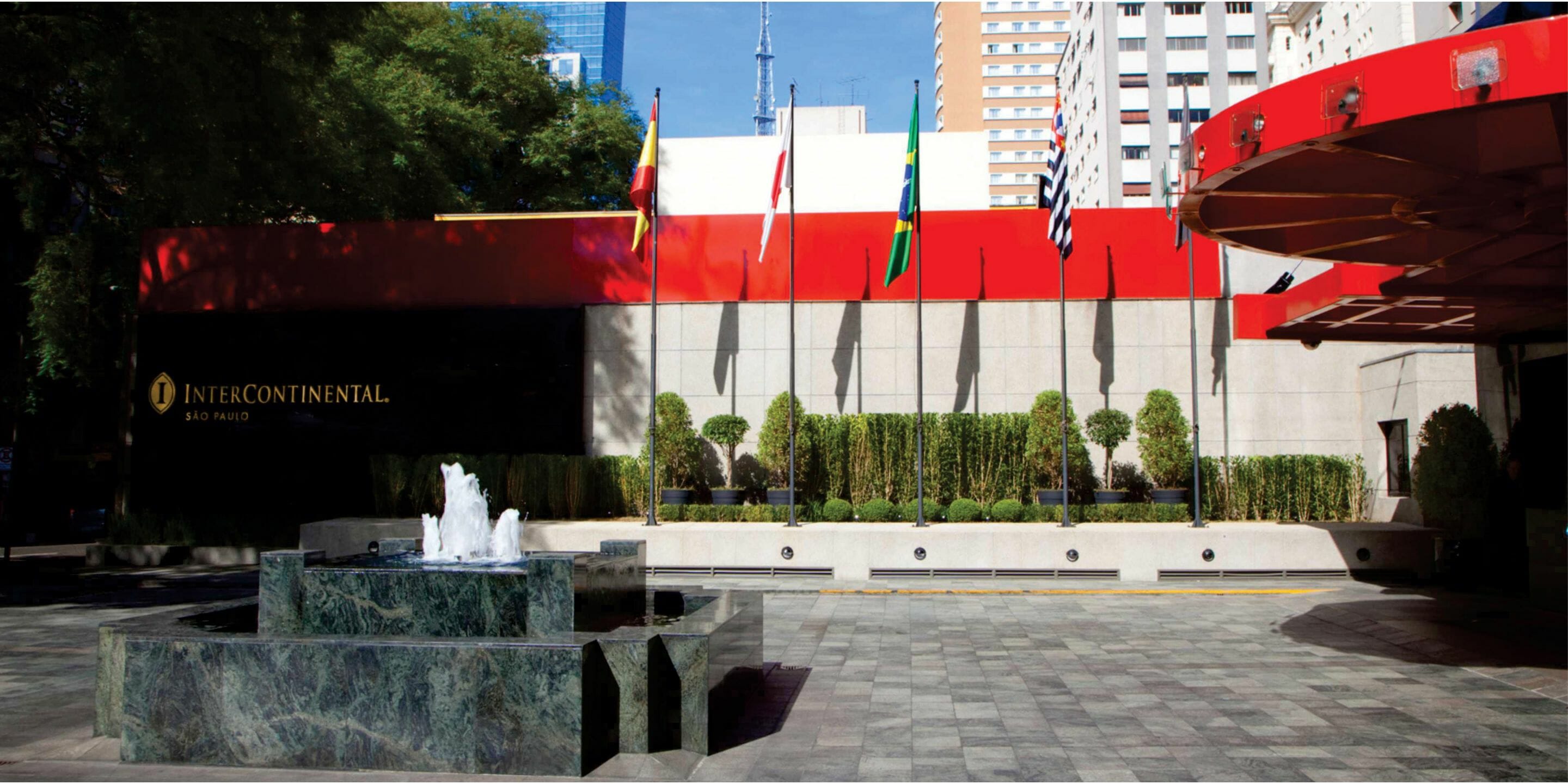 a fountain with flags in front of a building
