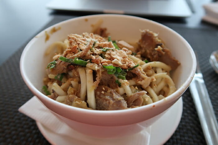 a bowl of noodles with meat and green onions