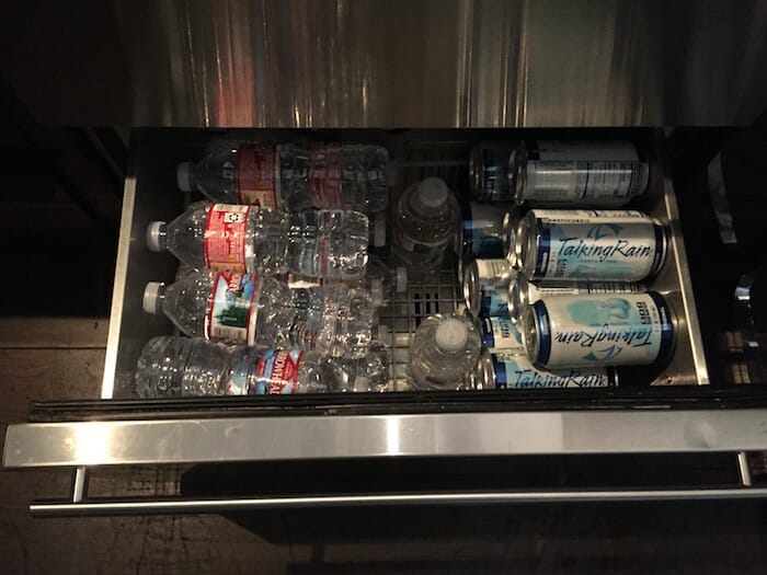 a refrigerator with bottles of water and cans