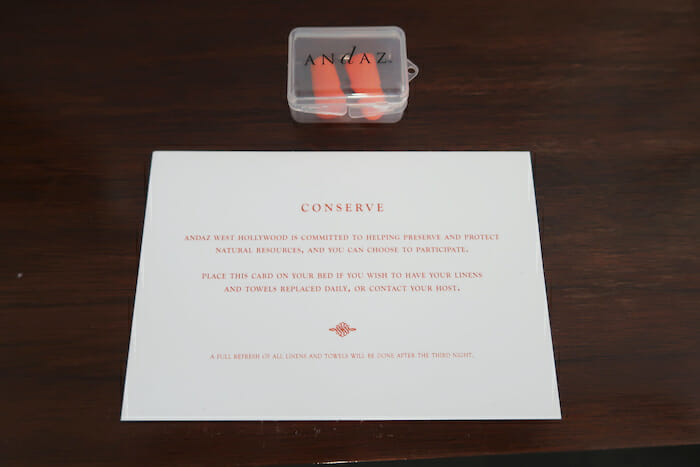 a white paper with orange earplugs in it next to a plastic container