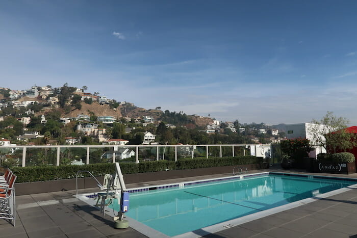 a pool with a fence and a hill in the background