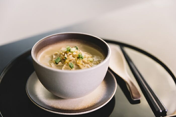 a bowl of soup with green onions and a spoon