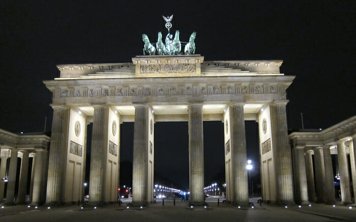 a large stone structure with pillars with Brandenburg Gate in the background