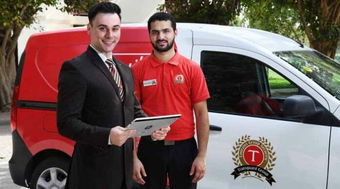 a man holding a tablet next to a man standing next to a van