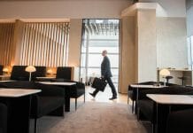 a man walking in a room with chairs and a briefcase