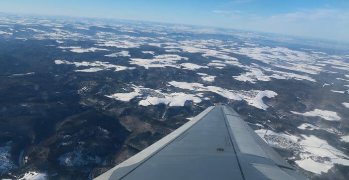 an airplane wing over a snowy landscape