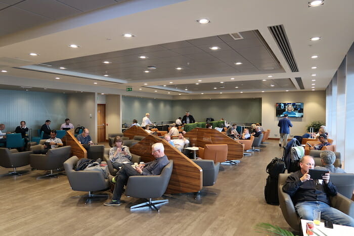 a group of people sitting in chairs in a room with luggage