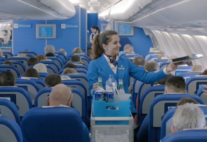 a woman in blue uniform handing a black card to a man in a plane