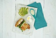 a croissant sandwich with avocado and egg on a marble board