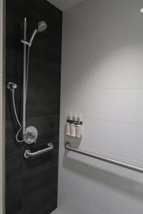 a shower with a handrail and a shower head