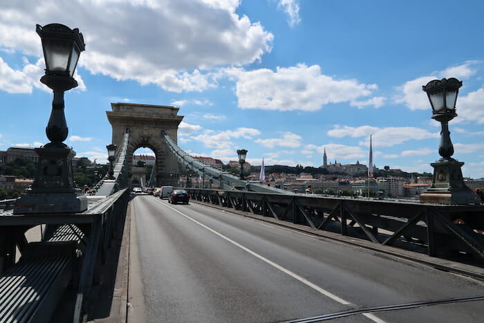 a bridge with a large arch and a road with cars and buildings in the background