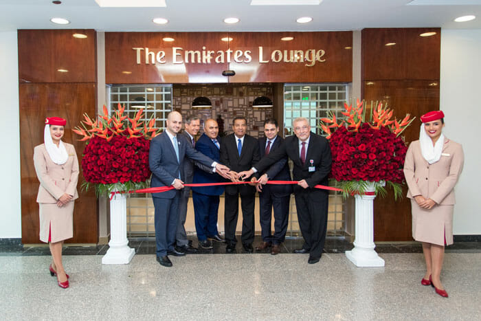 a group of men in suits cutting a red ribbon