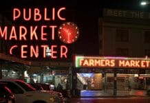 a neon sign at night with Pike Place Market in the background