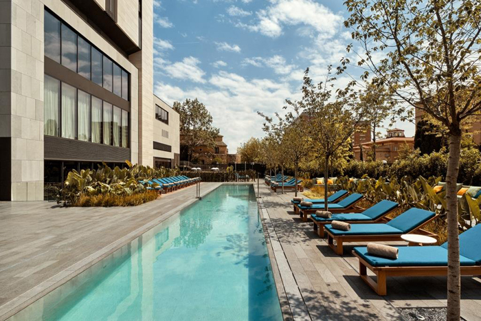 a pool with lounge chairs and trees in front of a building