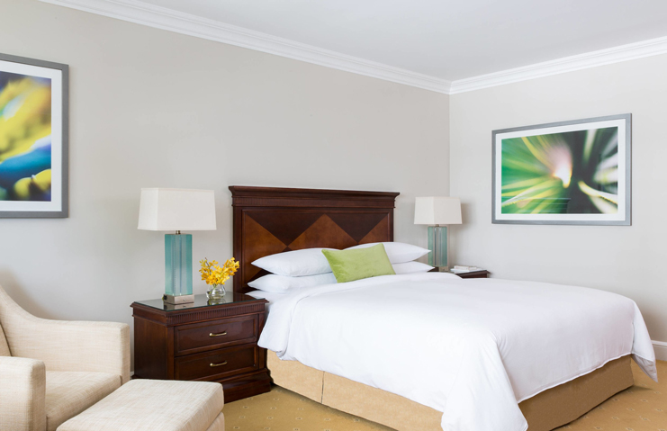 a bed with white sheets and green pillows in a room